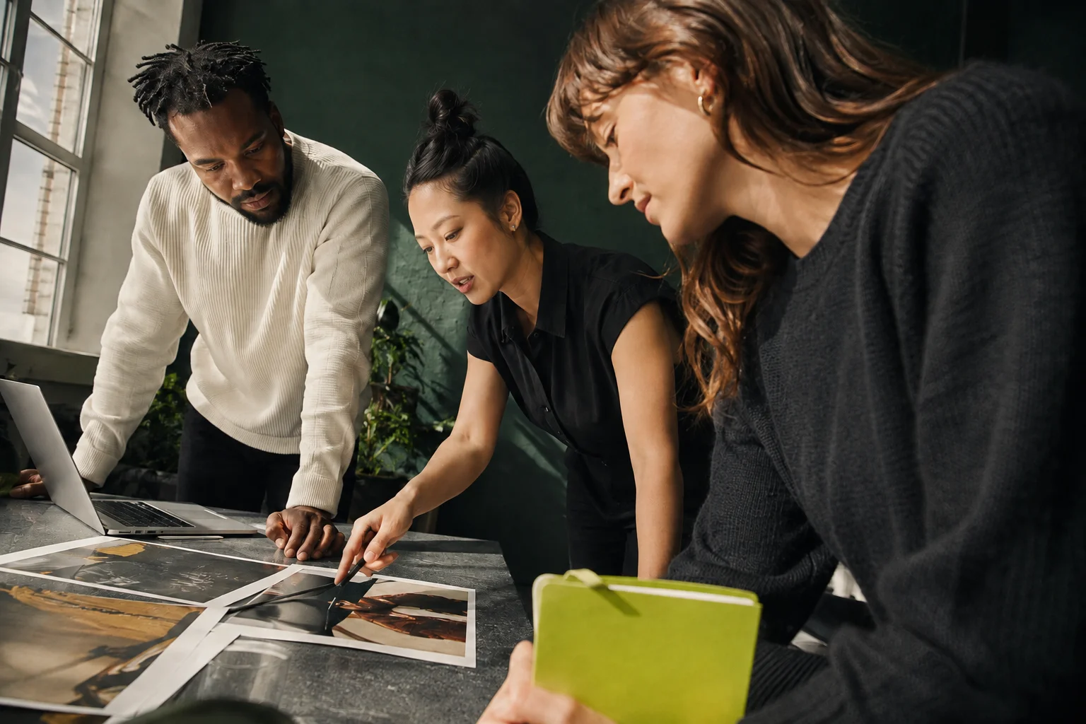 Three creative strategists reviewing campaign materials in a sunlit studio